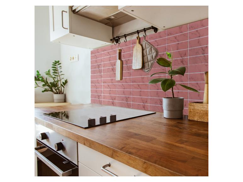 Cuisine moderne avec comptoir en bois, plaque de cuisson noire et carreaux roses effet marbre.