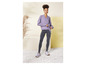 Une femme porte un pull lilas, un jean et des baskets.