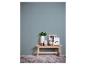 Mur bleu clair avec un banc en bois, des vases, une main en bois et des cadres, un avec le mot 'dream'.