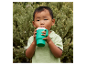 Un jeune enfant boit dans une tasse verte à bec verseur.