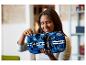Une femme tient une voiture modèle LEGO Technic Ford GT bleue avec des rayures blanches.