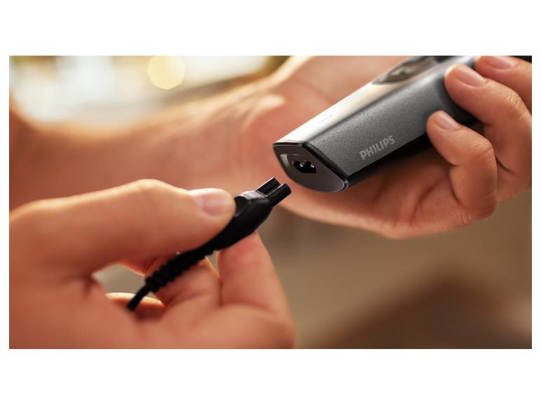 Mains connectant un chargeur à un rasoir électrique gris.