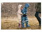 Deux enfants en vêtements imperméables avec un motif floral et des bottes de pluie bleues sont sous la pluie.