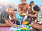 Des amis profitent d'un pique-nique avec des collations et des boissons sur la plage.