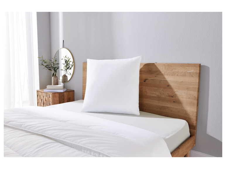 Une couette et un oreiller blancs sur un cadre de lit en bois.