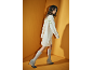 Femme portant une robe pull en maille et des bottes en maille grises sur fond jaune.