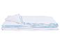Couette blanche pliée avec passepoil bleu.