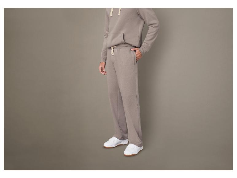 Homme en sweat-shirt et pantalon de survêtement gris.