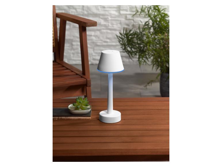 Une lampe blanche avec un abat-jour en forme de lanterne sur une table en bois.