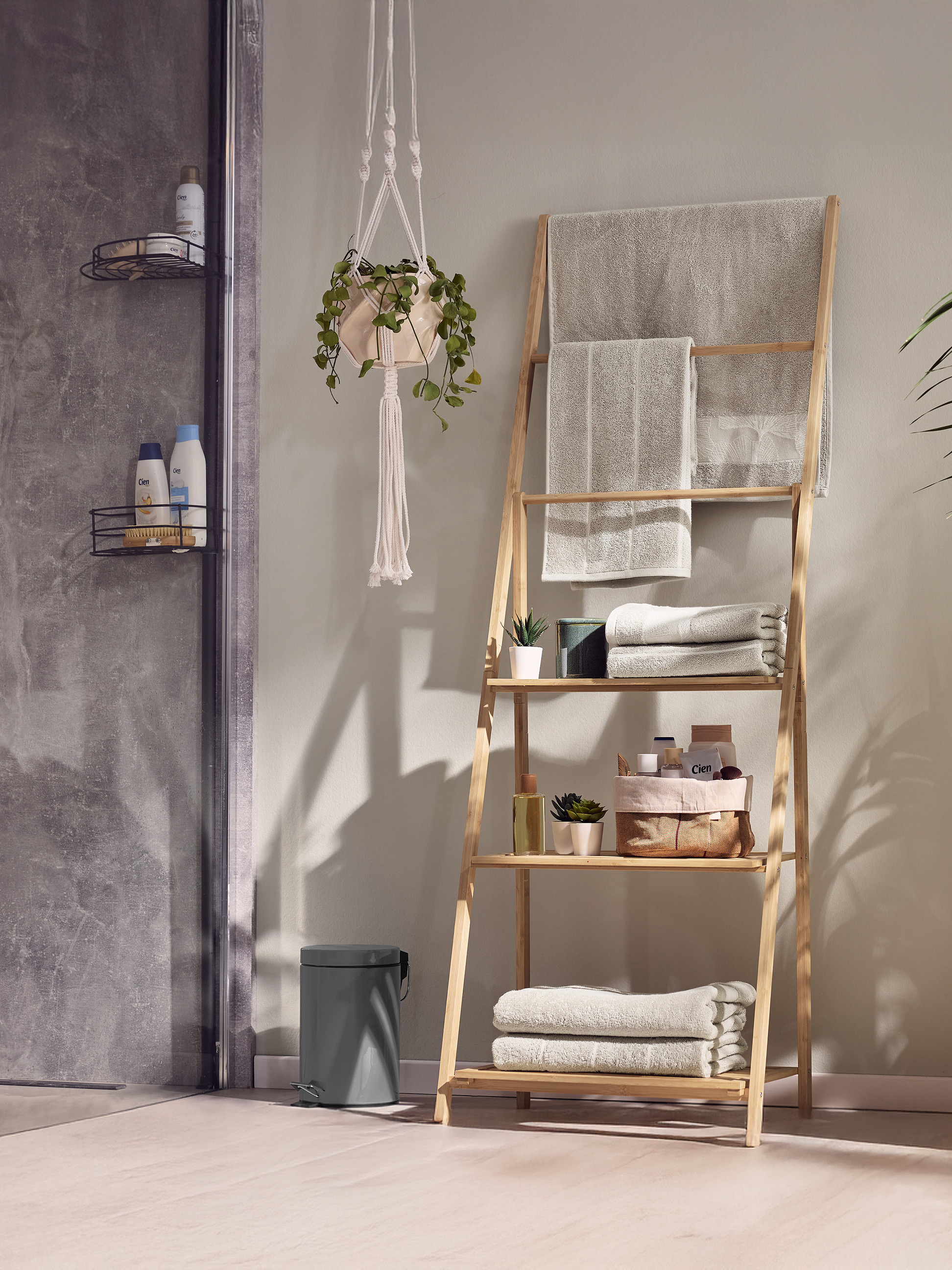 Étagère échelle en bambou avec serviettes et produits de bain dans une salle de bain moderne.