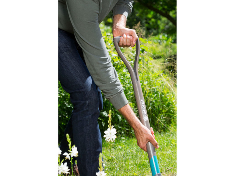 Une personne creuse dans le jardin avec une pelle Gardena.