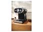 Une machine à expresso noire de 1973 avec un indicateur de température et des grains de café sur un comptoir en bois.