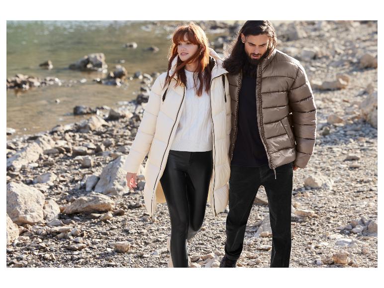 Une femme et un homme portant des vestes d'hiver marchent sur une berge rocheuse.