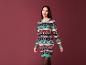 Une femme porte un pull de Noël vert à motifs de chats.
