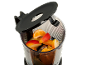 Morceaux de fruits dans un mixeur, dont orange, pomme et mangue, avec le couvercle ouvert.