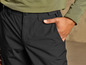 Pantalon noir avec des poches, porté par une personne portant un pull vert.