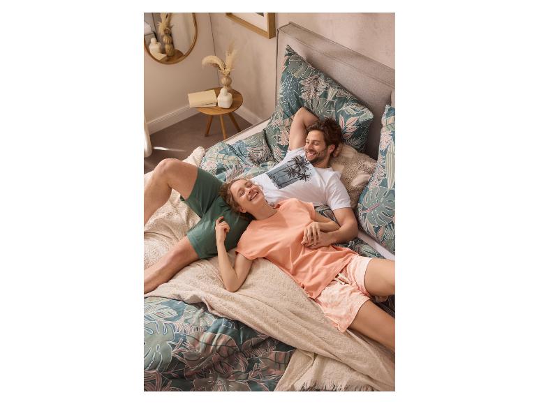 Couple en pyjama imprimé tropical se relaxant sur un lit avec une housse de couette à motifs.