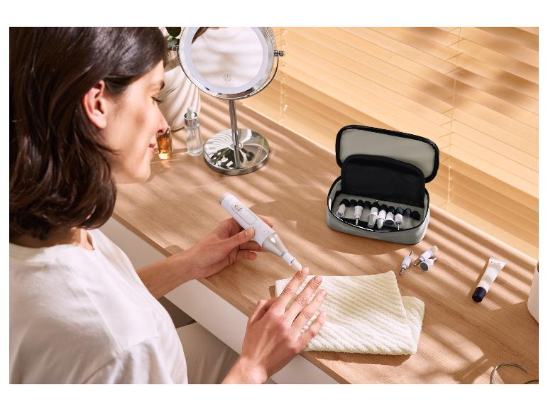Femme utilisant une lime à ongles électrique avec un kit de manucure sur une table en bois.