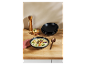 Soupe crémeuse servie dans un bol noir avec des croûtons et une cuillère en cuivre.