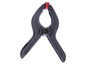 Une pince en plastique noire avec un bouton rouge.