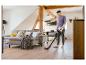 Homme passant l'aspirateur sans fil sur un parquet clair dans un salon moderne.