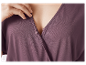 Une femme ajuste une robe violette à boutons.