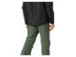Homme portant une veste noire et un pantalon vert zippé.
