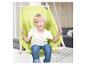 Un enfant blond souriant est assis dans une chaise balançoire verte, à l'intérieur.