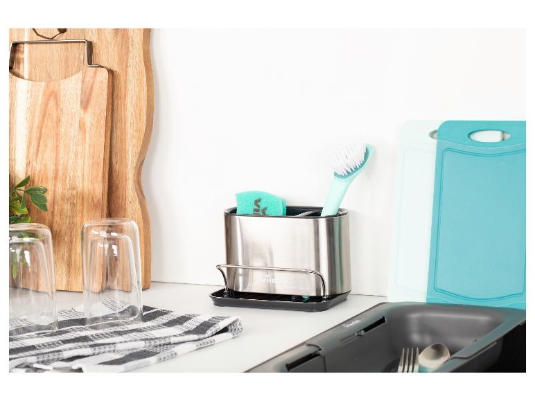 Support d'évier de cuisine avec éponge et brosse, à côté de planches à découper en bois et en plastique.