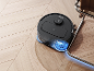 Robot aspirateur laveur nettoyant un parquet à côté d'une chaise