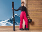 Une femme en tenue de ski avec des skis et un casque.