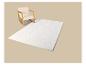 Fauteuil à bascule en bois clair et tapis blanc à motifs ondulés sur fond beige.