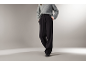 Femme en pull gris et pantalon large noir.