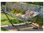 Femme se relaxant dans un hamac rayé bleu et beige avec un livre dans un jardin.