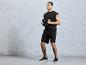 Un homme en short de sport noir et un t-shirt, tenant un disque de poids.