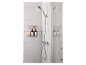 Douche avec douchette, étagère de douche avec flacons et éponges dans une salle de bain carrelée blanche.