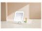 Un miroir de maquillage LED blanc avec ventouse sur une table, à côté d'un rouge à lèvres et d'un rouleau facial.