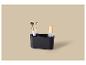 Organisateur de maquillage noir avec deux pinceaux et une bouteille sur fond beige.