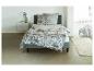 Un lit avec une tête de lit grise et une couette blanche à motif floral.