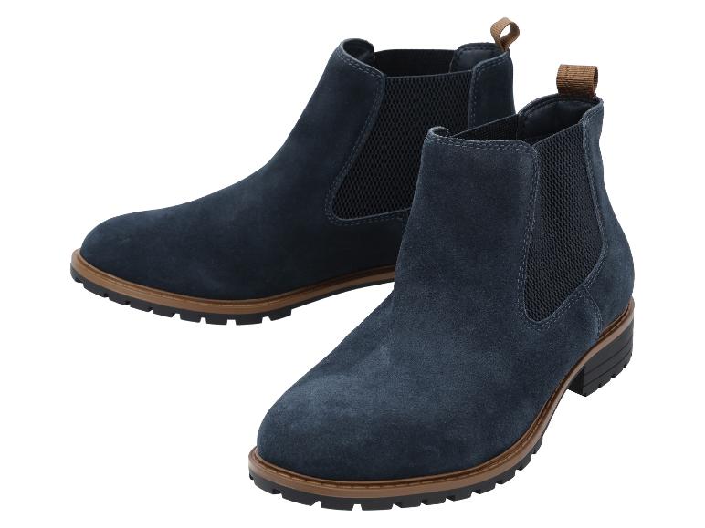 Une paire de bottines Chelsea en daim bleu avec une semelle marron et noire.