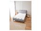 Cadre de lit gris avec matelas et tapis beiges.