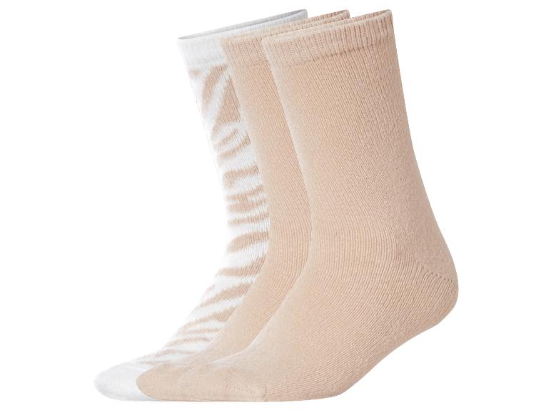 Trois paires de chaussettes beiges et blanches, dont une à rayures zébrées.