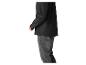 Homme portant une veste noire et un jean gris, vue de côté.