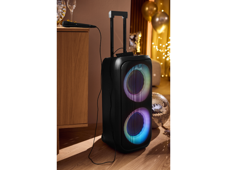 Grande enceinte portable avec lumières colorées et microfon dans une ambiance festive.