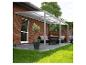 Pergola grise sur une terrasse en briques avec mobilier d'extérieur et pots.