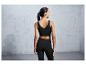 Une femme porte un soutien-gorge de sport noir et un legging.