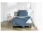 Parure de lit bleue sur un lit gris avec table de chevet et lampe dans une chambre.