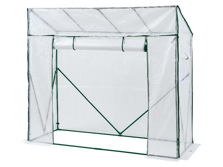 Une serre de jardin blanche avec porte enroulable et cadre vert.