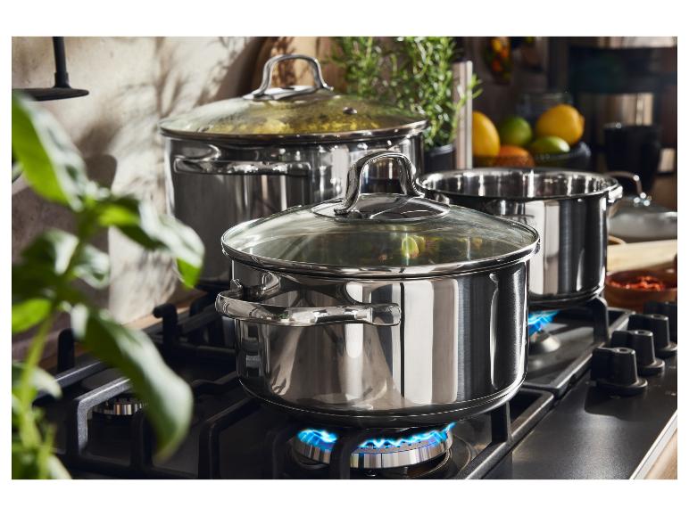 Casseroles en acier inoxydable sur une cuisinière à gaz avec des flammes bleues.