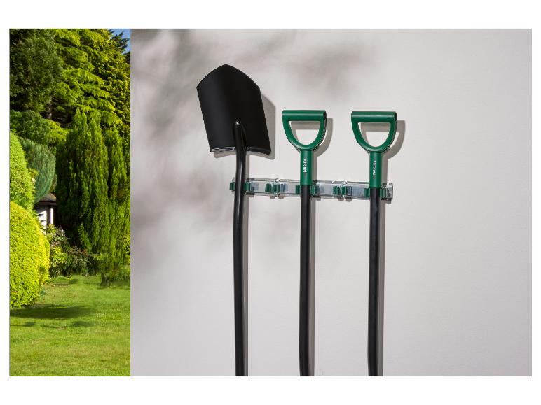Outils de jardin Parkside: pelle et bêches accrochées à un mur dans un jardin.